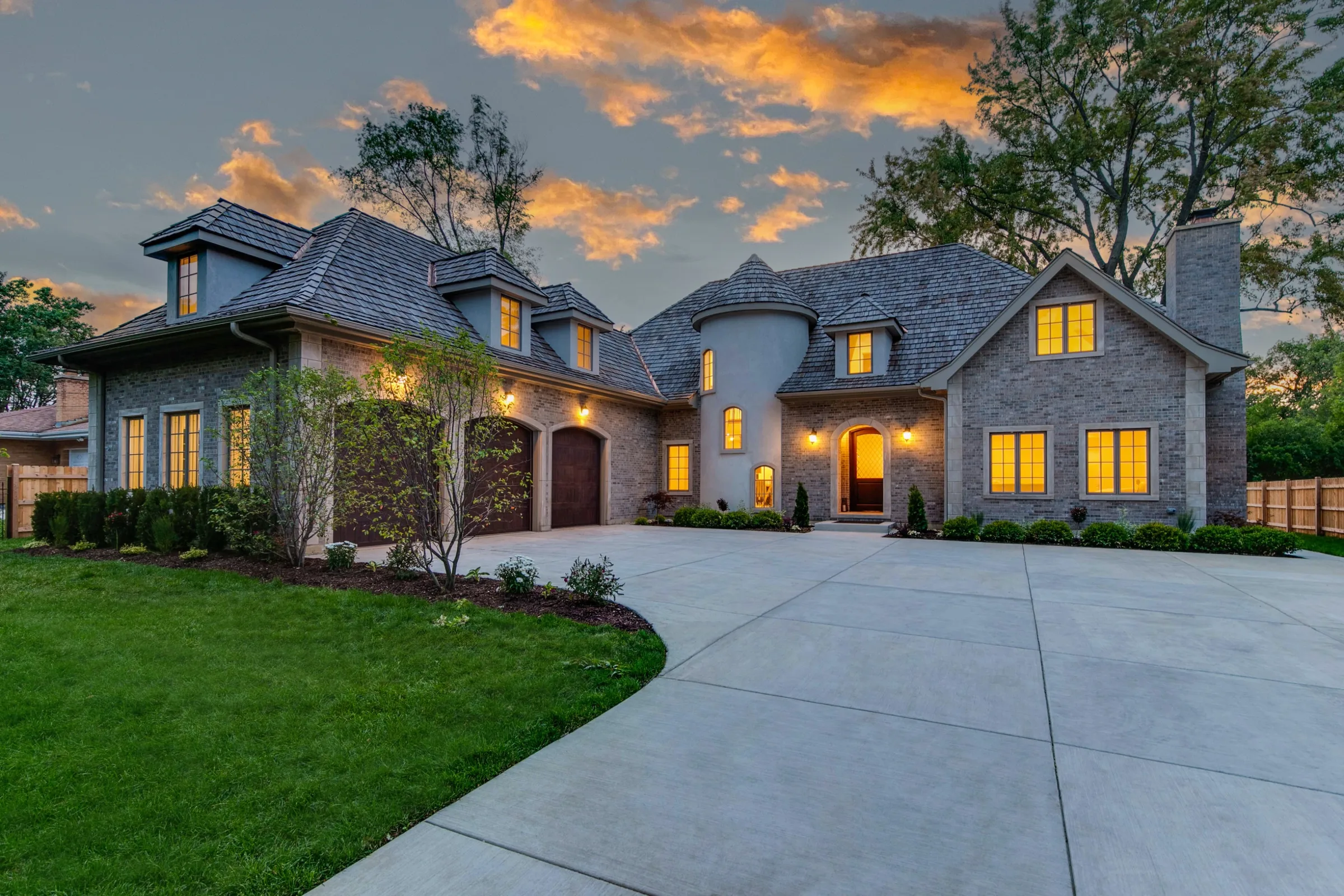 Residence 854 at dusk, stone front facade with turret entry glowing from within