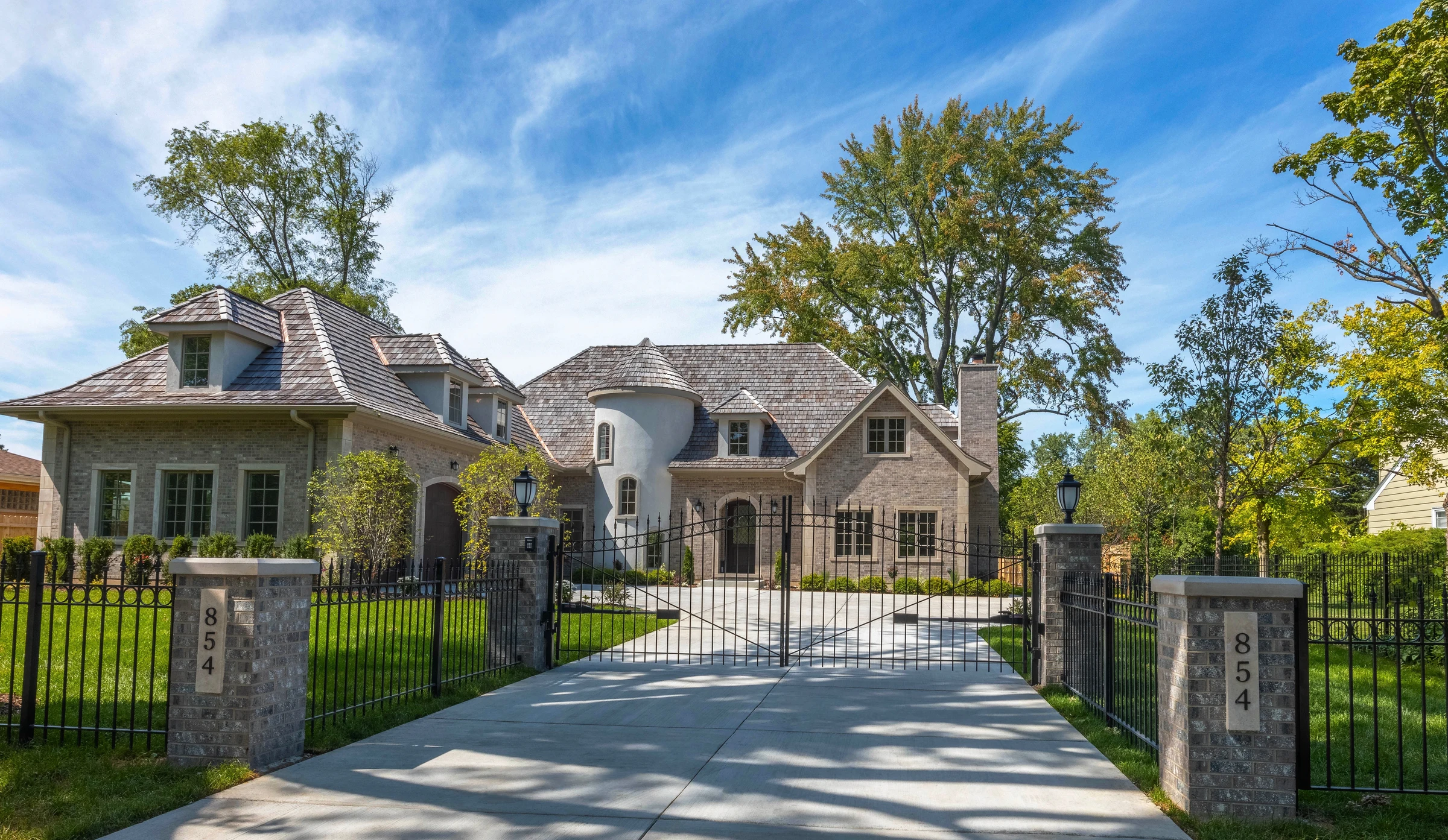 Residence 854 in daylight, gated brick and limestone facade with a cedar-shake roof