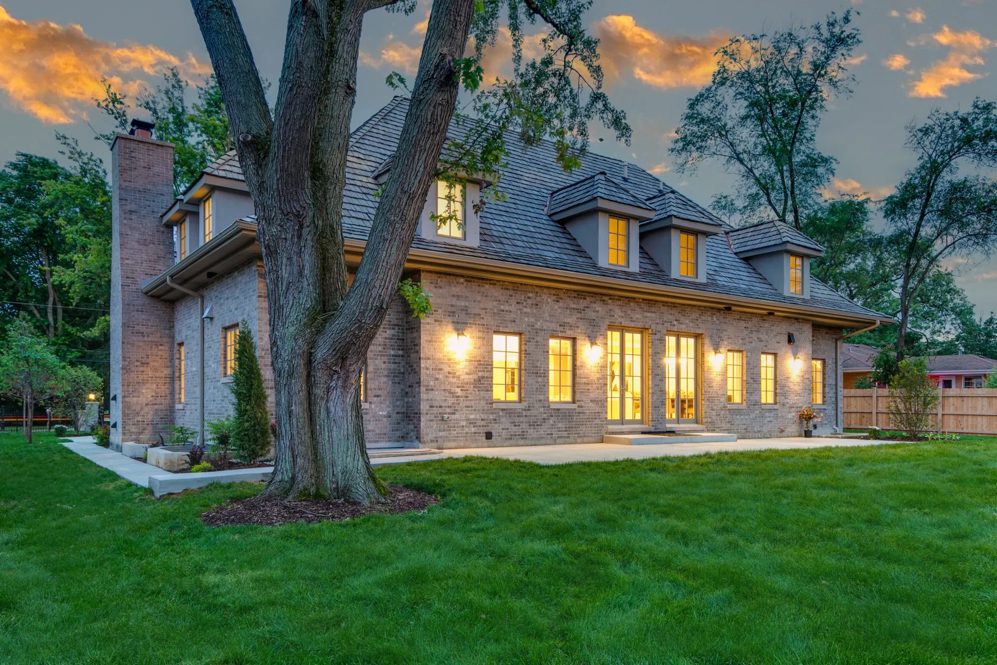 Rear corner of the residence at dusk, windows glowing warm