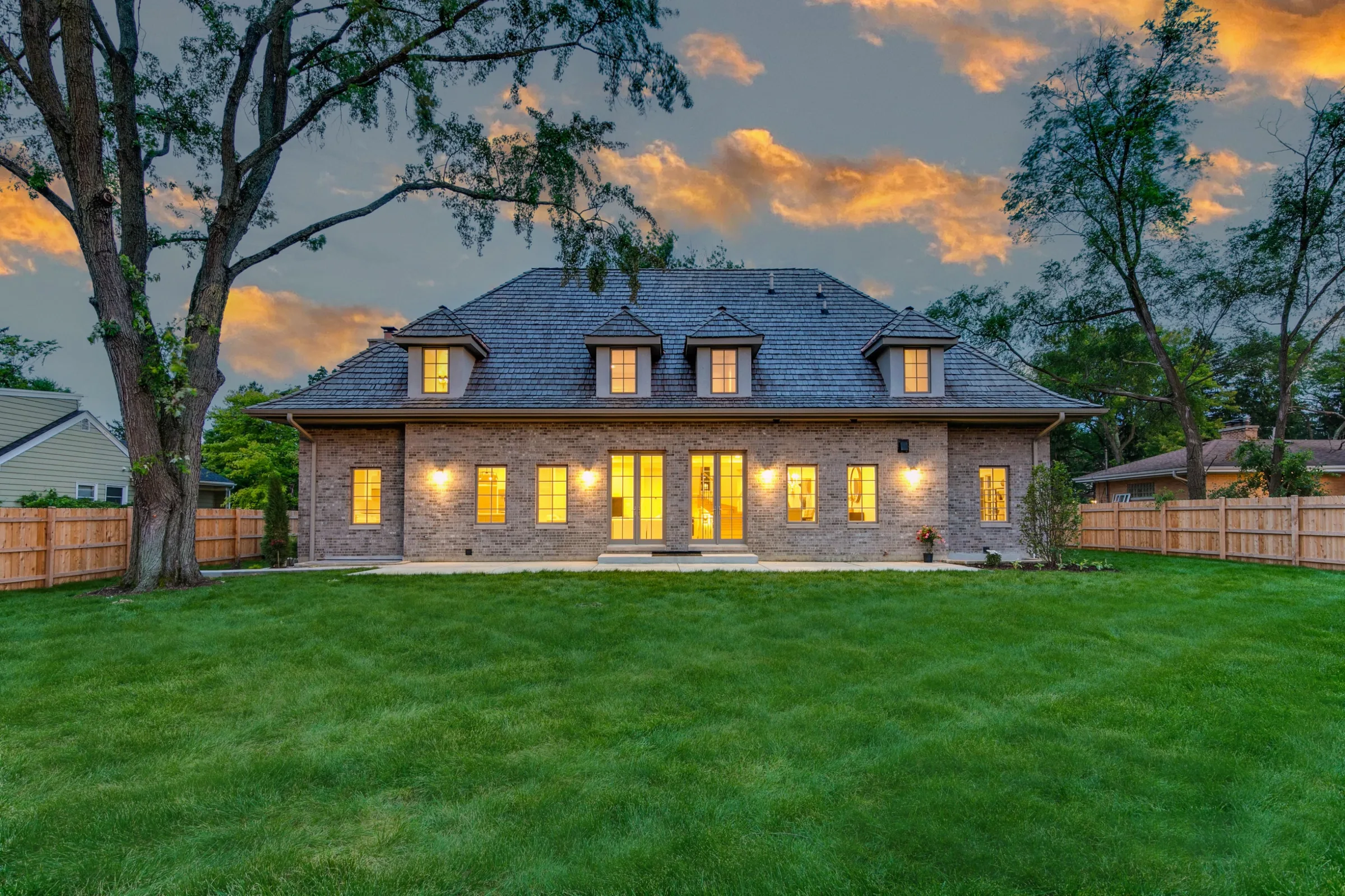 Rear elevation at dusk, lanterns lit across the garden facade