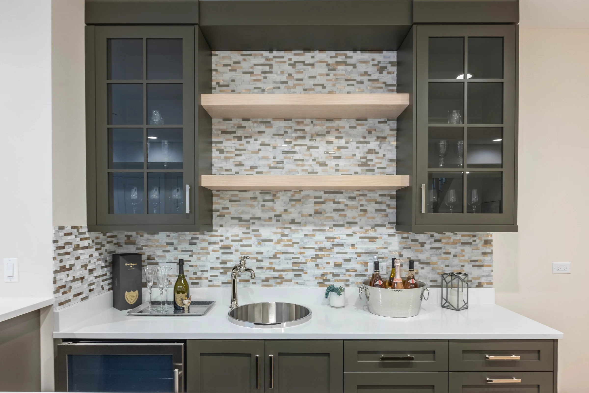 Wet bar with grey cabinetry, floating oak shelves and a mosaic backsplash