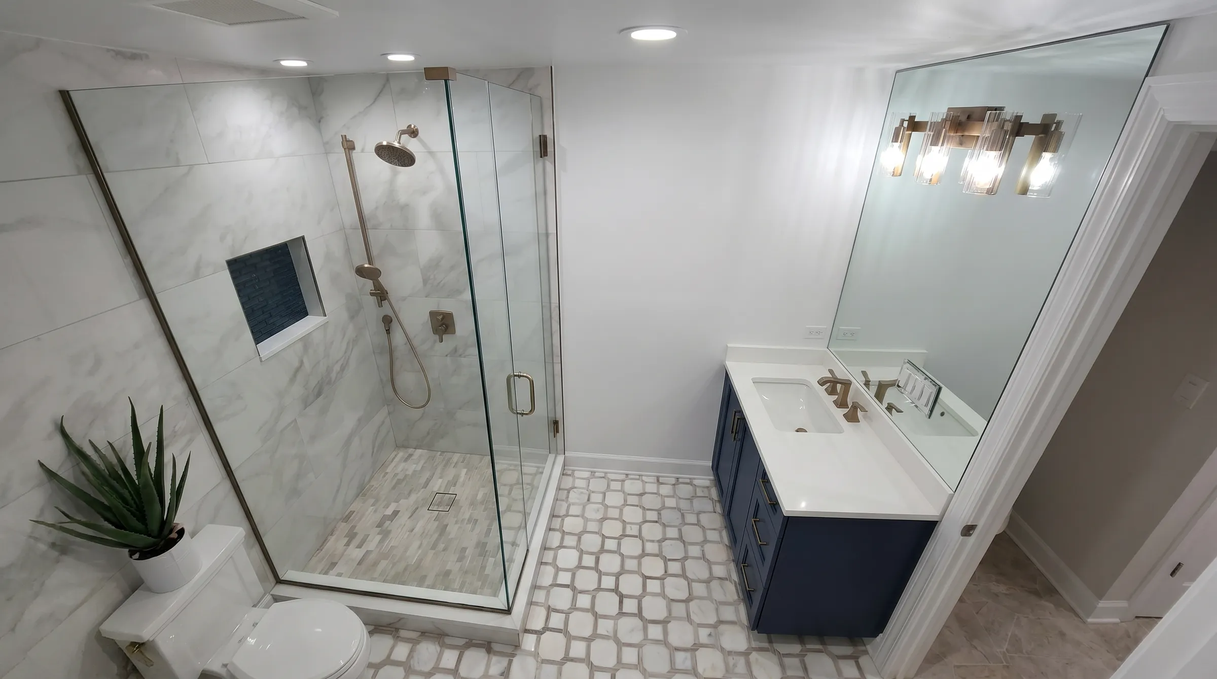 Marble guest bath with a glass shower and a deep blue vanity