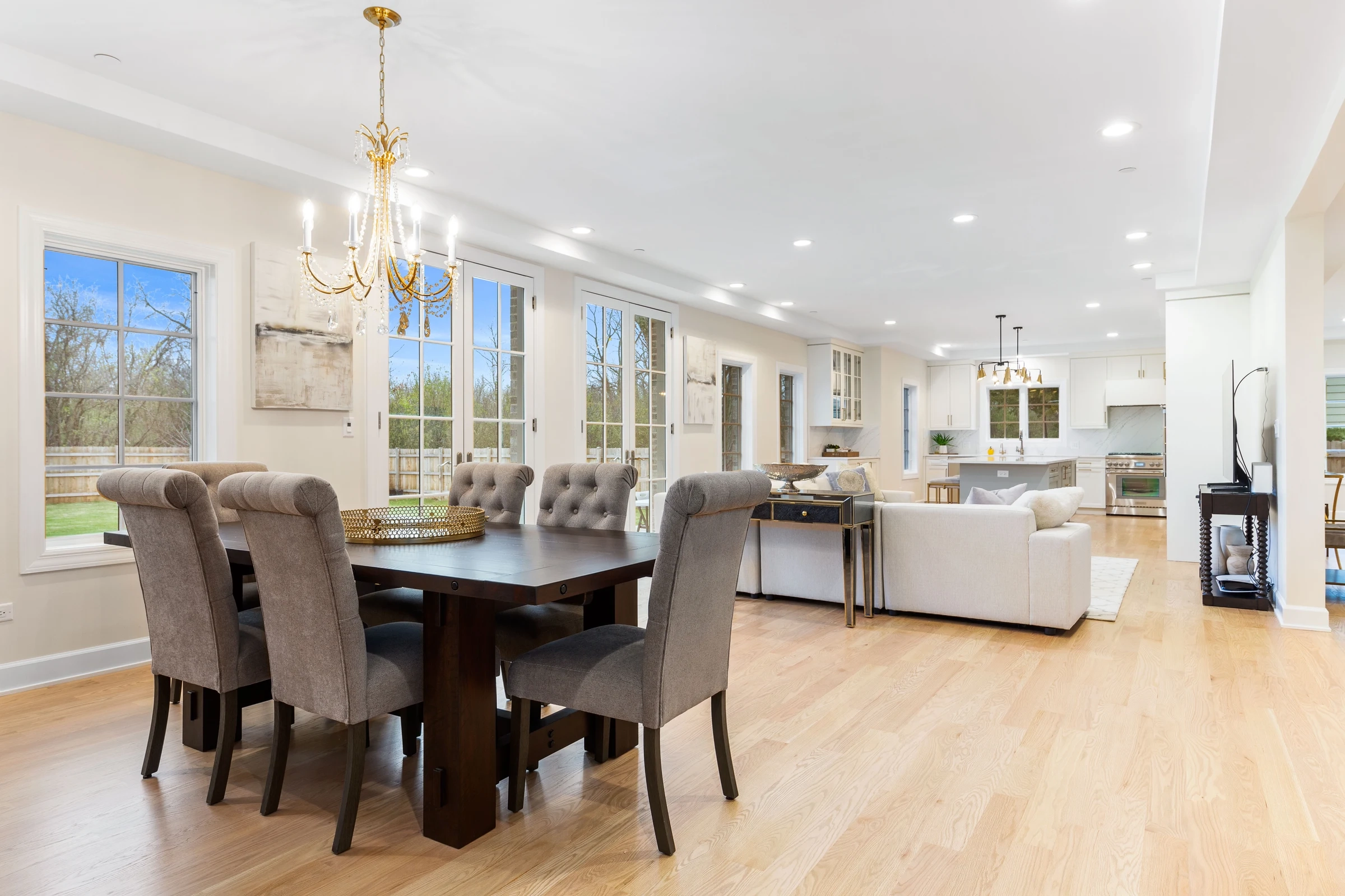 Dining room set beneath a chandelier, opening to the kitchen beyond