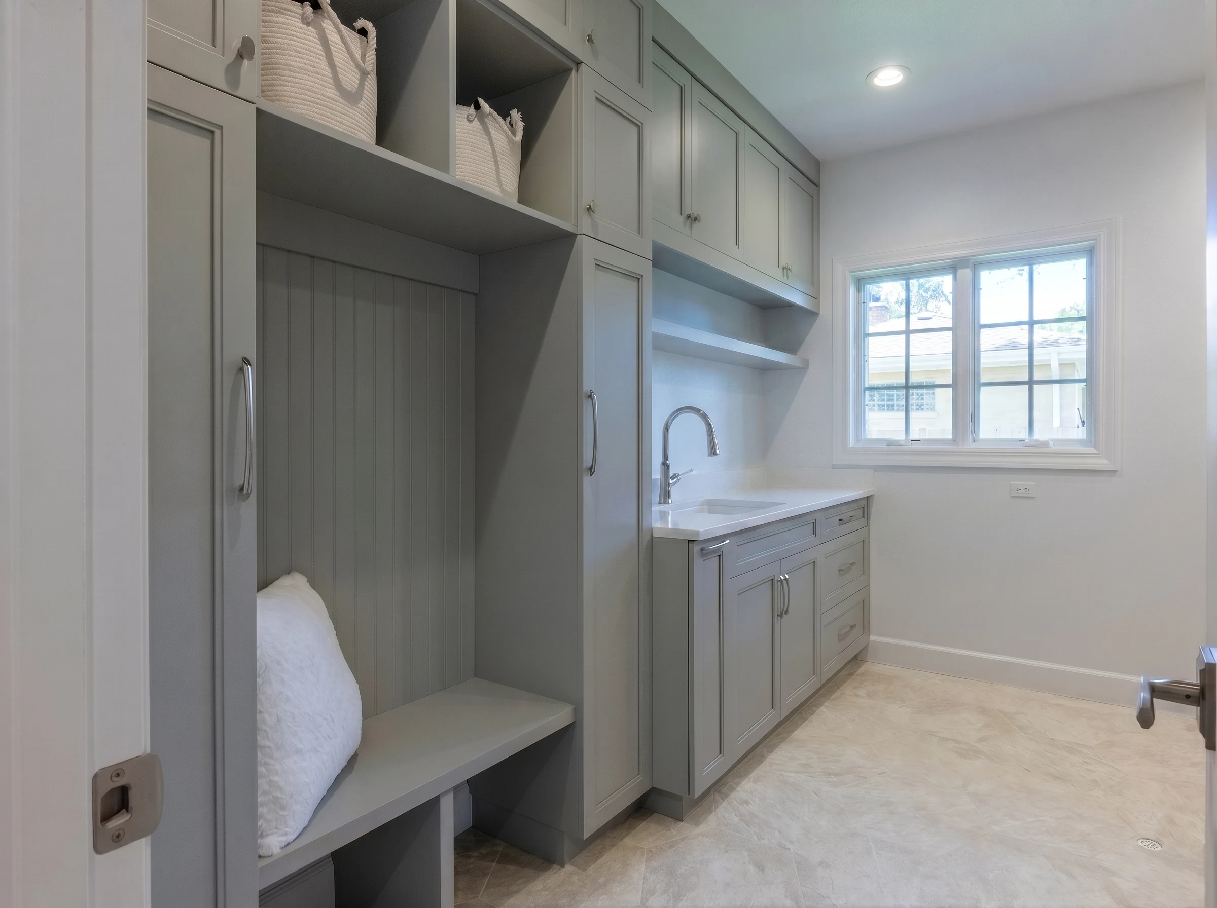 Laundry room with grey cabinetry, a deep sink and a sunny window