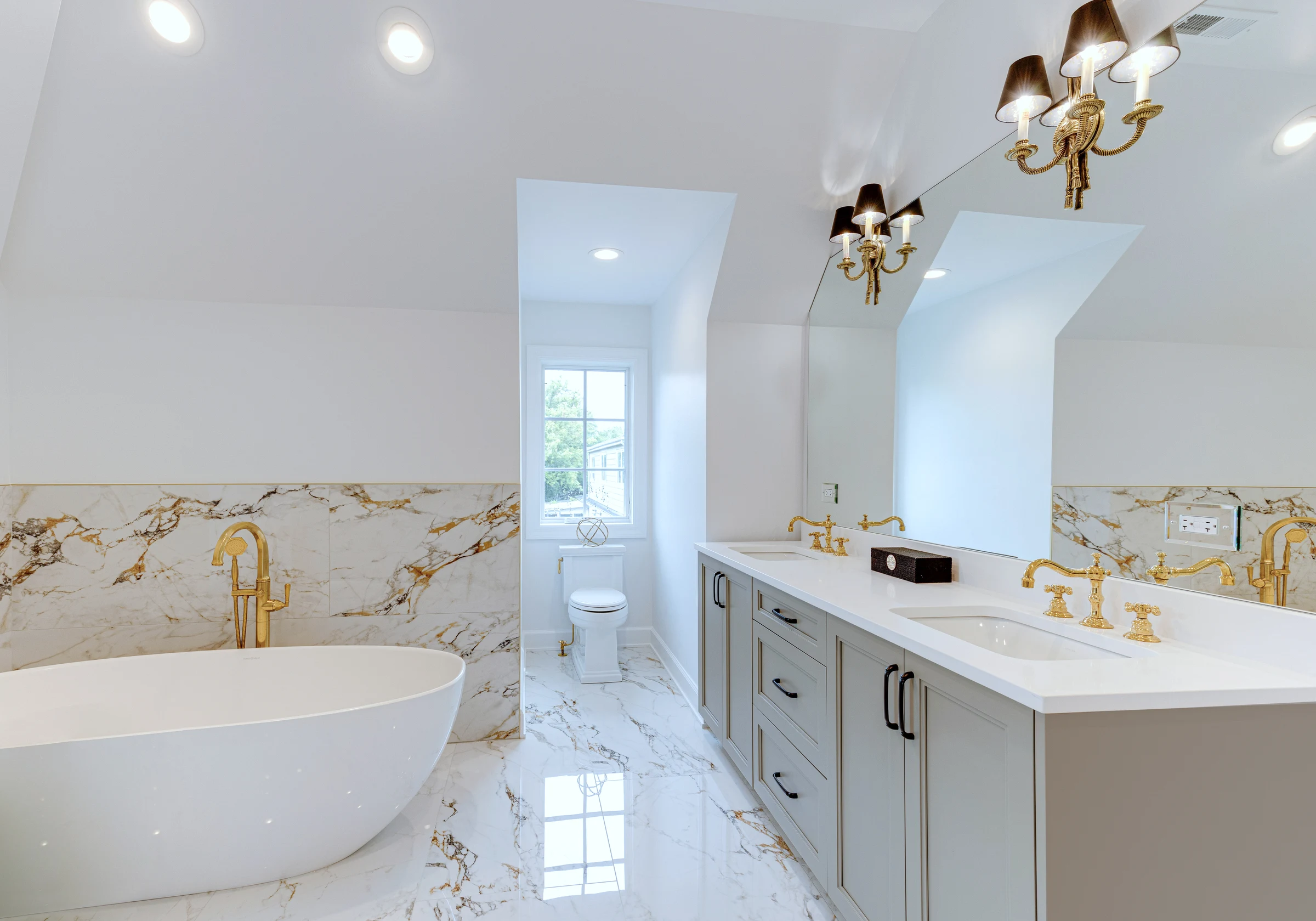 Principal bath vanity in marble with brass fittings, paired sconces and mirror