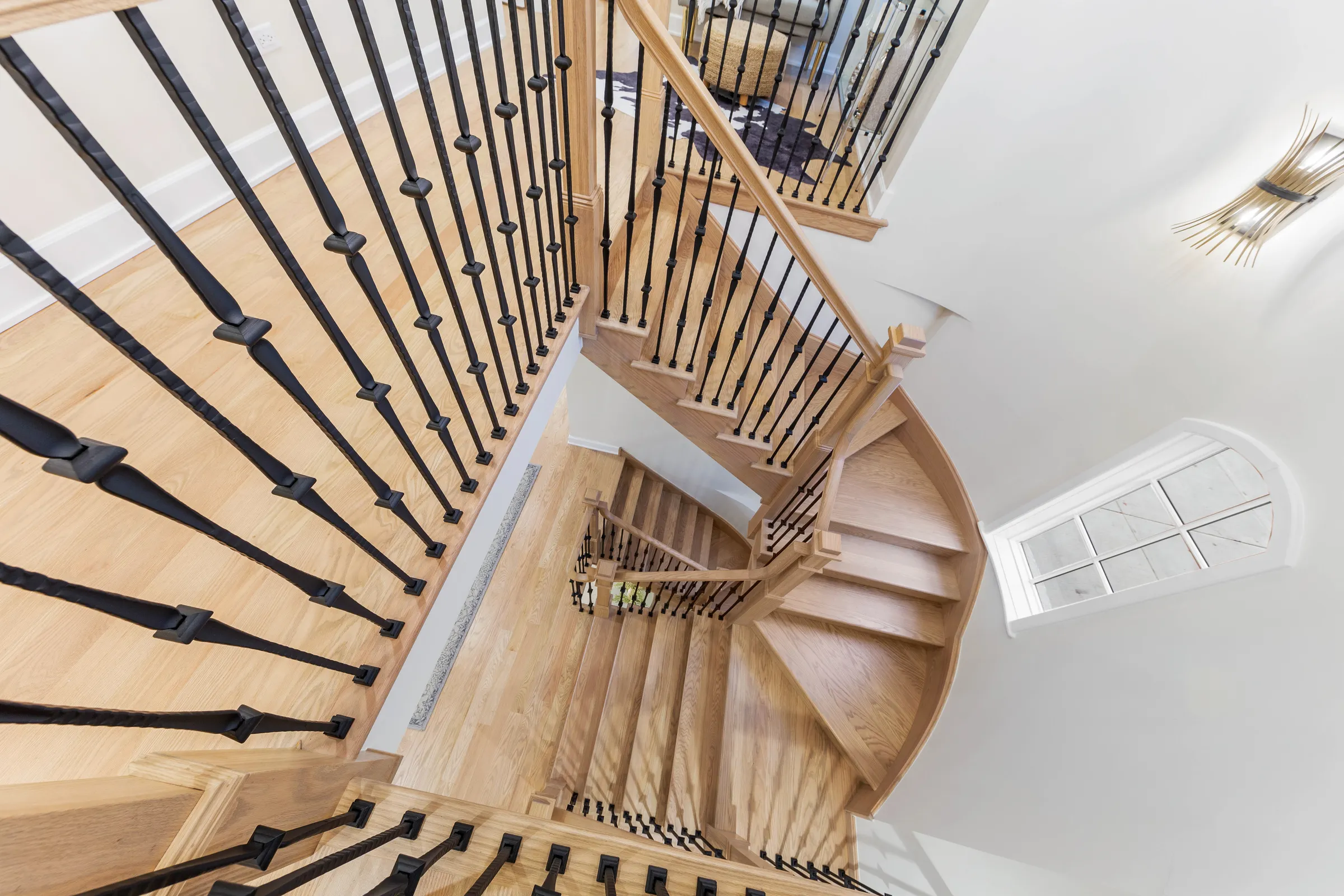 The oak staircase seen from above, coiling like a nautilus
